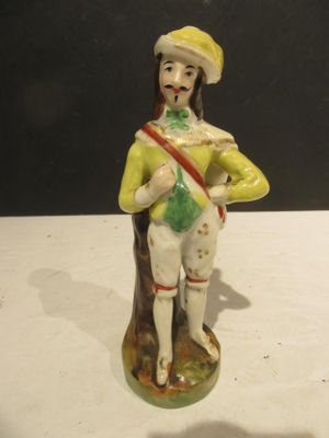a figurine of a man with a green hat and yellow jacket