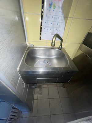 un évier en acier inoxydable dans le coin d'une toilette publique
