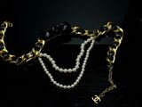 a close up of a necklace with pearls and a gold chain