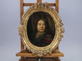 une image représentant un tableau d'une femme, dans un cadre doré, posé sur un chevalet en bois