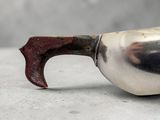 a silver spoon with a red handle on a table