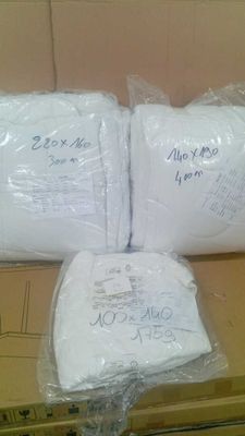 trois rouleaux de papier toilette emballés dans des sacs en plastique, posés sur une boîte en carton