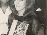 photographie en noir et blanc d'une femme tenant un livre devant un groupe de personnes