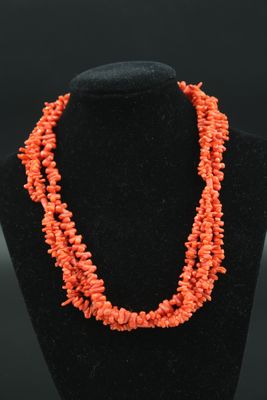 un collier composé de perles de corail, présenté sur un mannequin noir