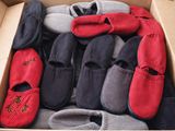de nombreuses paires de pantoufles dans une boîte posée par terre