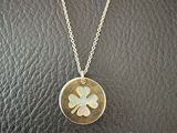 a necklace with a four leaf clover on it sitting on a black leather surface