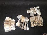 a lot of silver spoons and forks on a black table
