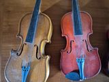 three violins are lined up on a shelf in a room