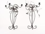 two metal candelabs with candles on them on a white surface