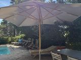 a table and chairs under an umbrella near a pool