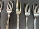 six forks are lined up in a row on a table