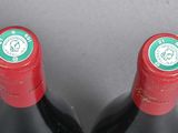 two bottles of red wine sitting next to each other on top of a table