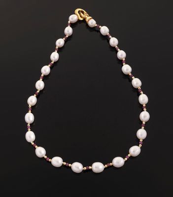 a white pearl and ruby beaded necklace on a black background