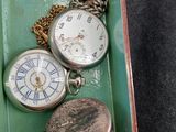 many different types of pocket watches in a green tray