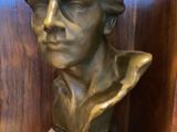 two bronze busts of men sitting on a wooden shelf