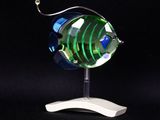 a glass fish on a white stand on a black background