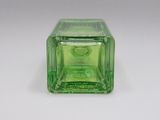 une bouteille en verre verte avec un bouchon vert posée sur une surface blanche