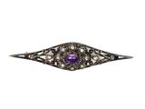 un gros plan sur une pierre violette sertie dans une broche en argent