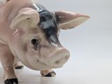 a ceramic pig figurine that is standing on a white surface