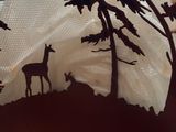 a paper cut of a deer and trees on a pillow