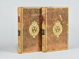 pair of antique leather books with gold emblems on them