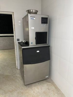 une machine à glaçons argentée et noire, dans un coin de la pièce