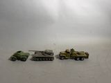 three toy army vehicles are lined up on a white surface