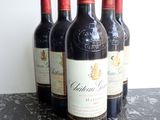 four bottles of red wine are lined up on a marble table