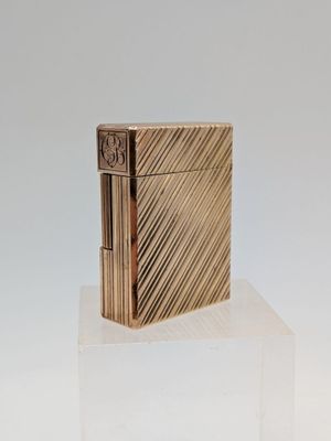 un briquet doré posé sur un bloc de verre transparent