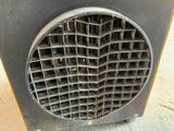 a metal fan that is sitting on the ground next to a wall