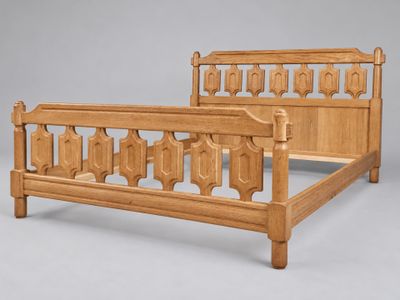 un lit dont le cadre en bois présente des sculptures sur la tête de lit