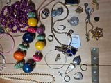 a lot of jewelry on a table with a cell phone
