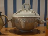 a white bowl with a lid sitting on a table next to two vases