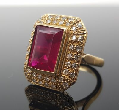 an image of a gold ring with a pink stone surrounded by white diamonds