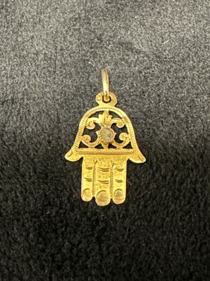 un gros plan d'un petit pendentif hamsa en or sur une surface noire