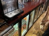 une personne debout devant un comptoir sur lequel sont posées des boissons