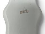 a small white vase with a gold writing on it