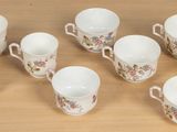 nine cups and a saucer sitting on a table