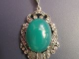 an image of a necklace with a green stone on it