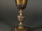 an antique silver cup with a gold rim on a grey background