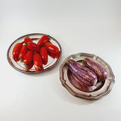 tomatoes and eggplant on a plate next to a bowl of eggplant