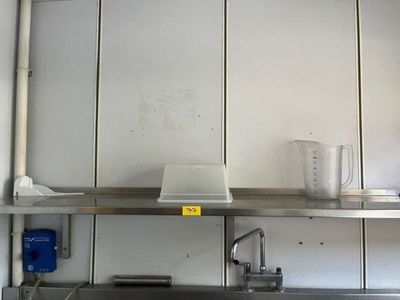 a kitchen with a stainless steel sink and a metal shelf