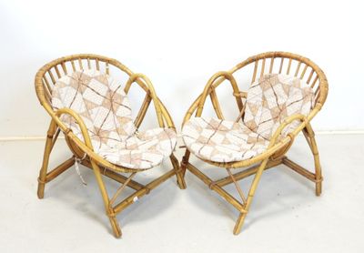 une paire de chaises en bambou avec des coussins à motifs dans une pièce blanche
