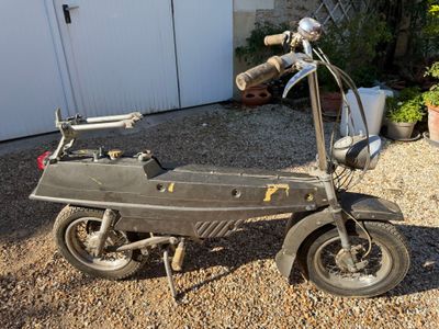 un petit scooter garé sur le gravier