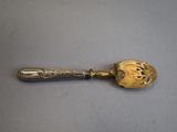 an antique silver spoon with a gold handle on a table
