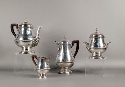 trois théières en argent et une cafetière posées sur un support