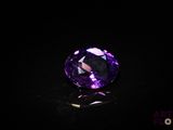 un gros plan d'une pierre précieuse violette sur une surface noire