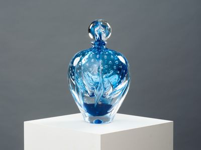 un vase en verre bleu posé sur un socle blanc