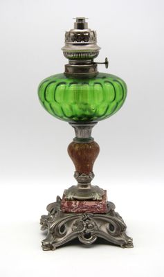 une lampe ancienne en verre vert avec un pied en métal, sur fond blanc
