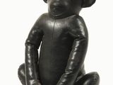 un singe noir assis par terre, les jambes croisées